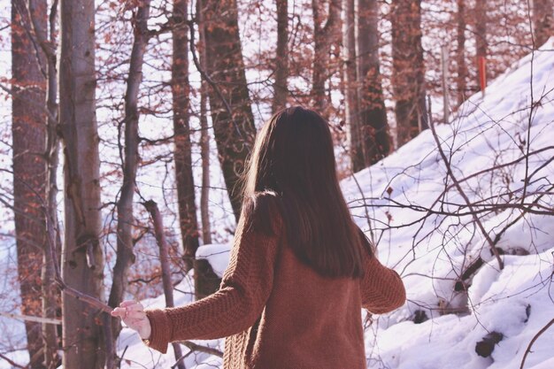 Foto vista trasera de una mujer en un bosque cubierto de nieve