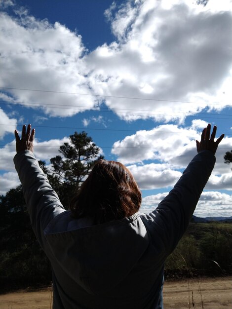 Foto vista trasera de una mujer con los brazos extendidos de pie contra el cielo