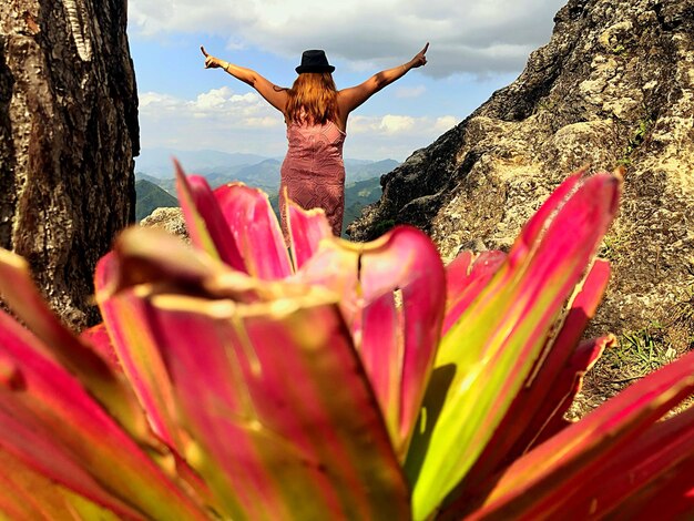 Foto vista trasera de una mujer con los brazos extendidos de pie en la montaña contra el cielo