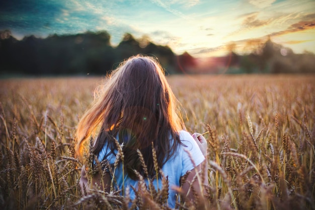 Vista trasera de una mujer caminando por el campo contra el cielo