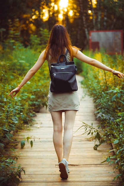 Foto vista trasera de una mujer caminando por el paseo marítimo en medio de plantas