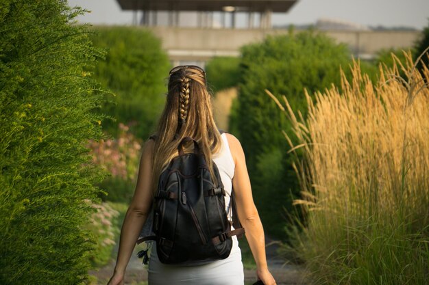 Vista trasera de una mujer caminando entre plantas