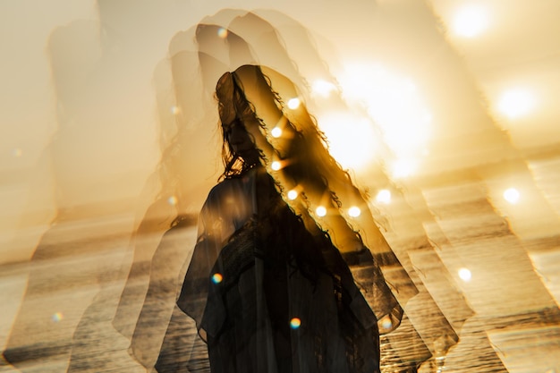 Vista trasera de una mujer caminando por la playa durante el atardecer