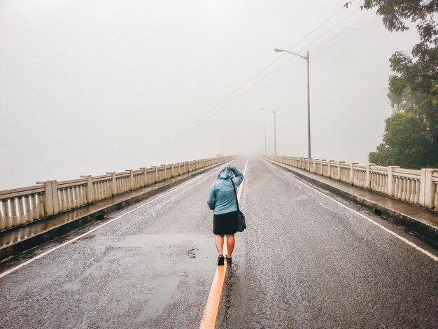 Foto vista trasera de una mujer caminando por un puente contra el cielo