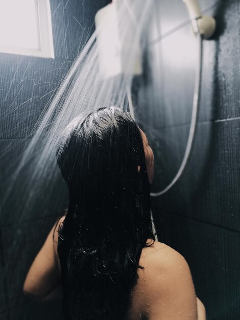 Foto vista trasera de una mujer sin camisa en el baño