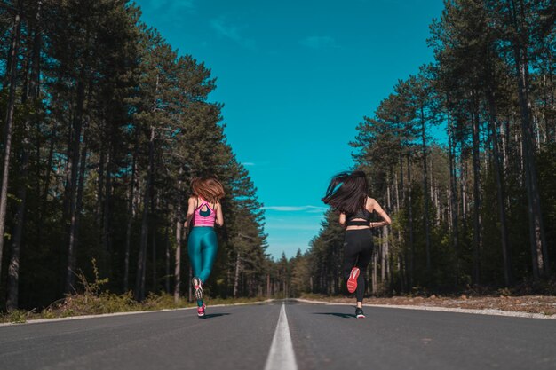 Foto vista trasera de una mujer corriendo por la carretera contra los árboles