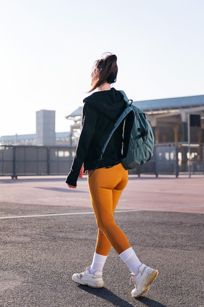 Vista trasera de una mujer deportiva caminando por la calle
