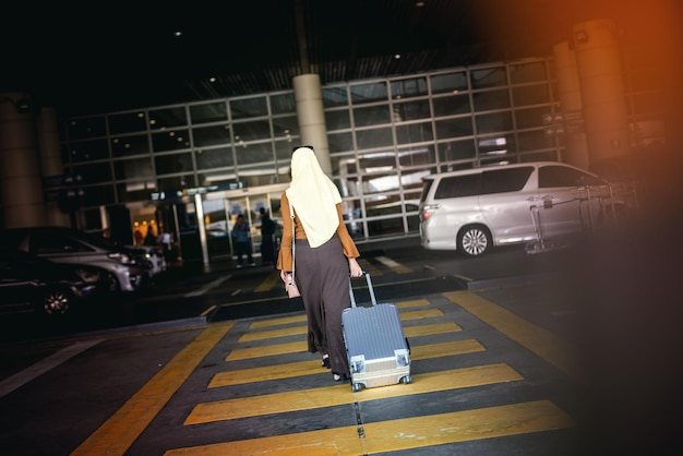 Foto vista trasera de una mujer con equipaje caminando en el aeropuerto