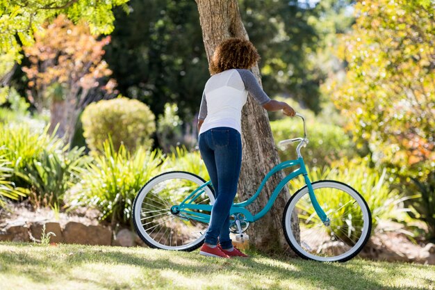 Vista trasera de la mujer estacionando su bicicleta