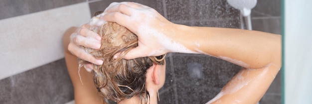 Vista trasera de una mujer feliz lavando el cuerpo y el cabello con agua caliente