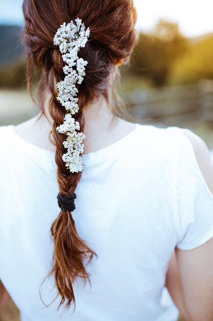 Foto vista trasera de la mujer con la flor blanca