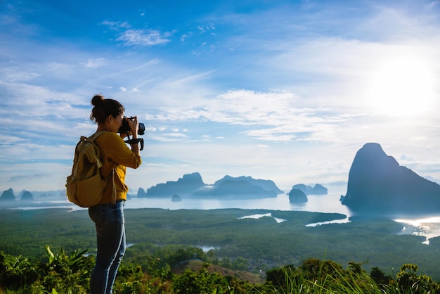 Vista trasera de una mujer fotografiando en la montaña contra el cielo