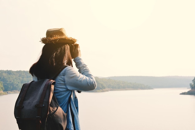 Vista trasera de una mujer fotografiando un paisaje contra un cielo despejado
