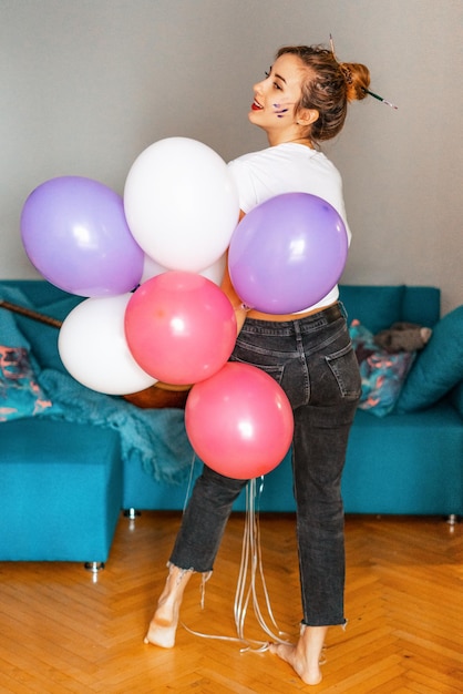 Foto vista trasera de una mujer con globos en casa