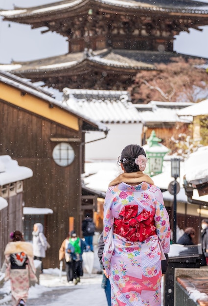 Vista trasera de una mujer joven asiática con kimono tradicional japonés en la calle Sannenzaka con nieve