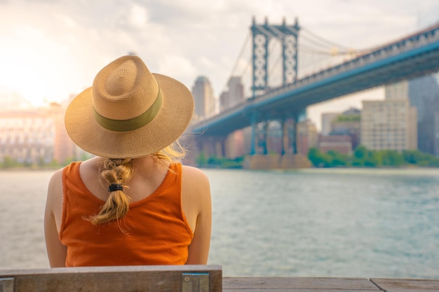 Vista trasera de una mujer joven atractiva con sombrero en la ciudad de Nueva York Concepto de libertad y aventura de viaje