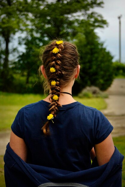 Foto vista trasera de una mujer joven con el cabello trenzado y flores