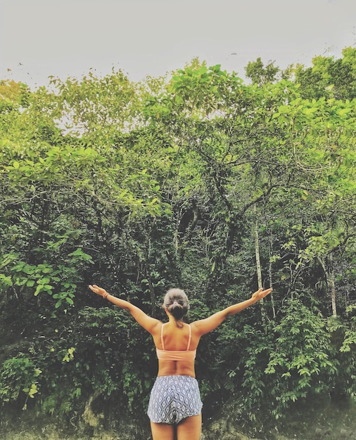 Foto vista trasera de una mujer joven de pie junto a un árbol