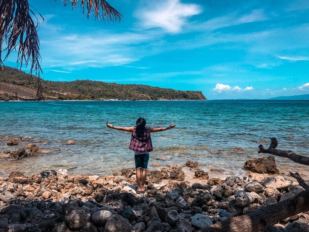 Foto vista trasera de una mujer joven de pie en la playa