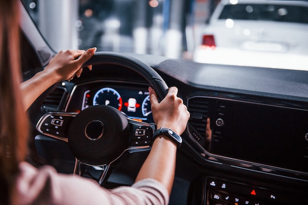 Vista trasera de una mujer joven que se encuentra dentro de un automóvil moderno nuevo.