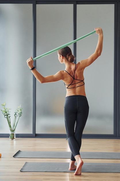 Vista trasera Mujer joven en ropa deportiva y con cuerpo delgado tiene día de yoga fitness en interiores