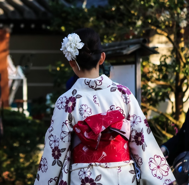 Vista trasera de una mujer en kimono contra un árbol