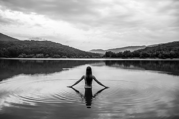 Vista trasera de la mujer en el lago contra el cielo