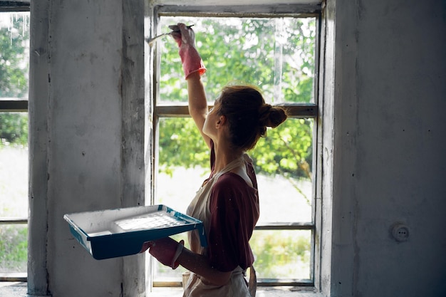 Vista trasera de una mujer leyendo un libro contra la ventana