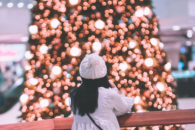 Vista trasera de la mujer por las luces iluminadas en el centro comercial