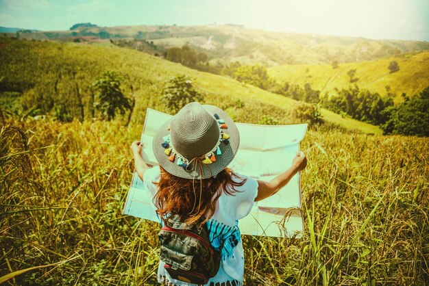 Foto vista trasera de una mujer con un mapa de pie en el campo contra el cielo