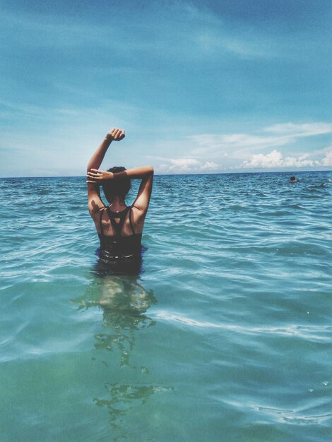 Foto vista trasera de una mujer en el mar contra el cielo