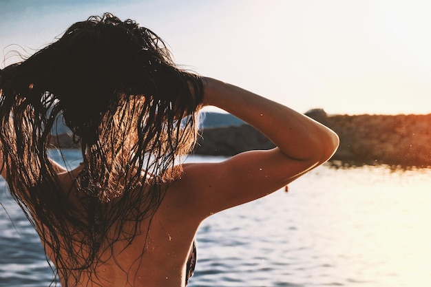 Vista trasera de una mujer en el mar contra el cielo
