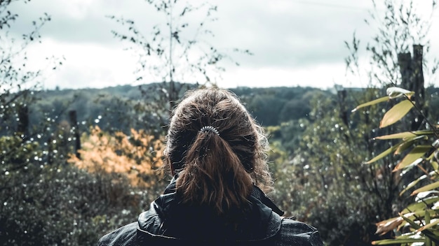 Vista trasera de una mujer mirando el bosque contra el cielo