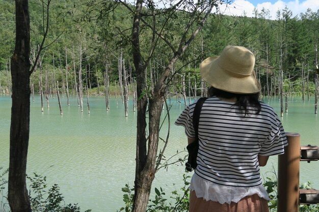Foto vista trasera de una mujer mirando un lago en el bosque