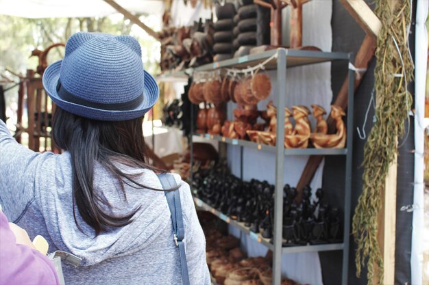 Foto vista trasera de una mujer mirando objetos para la venta en el mercado