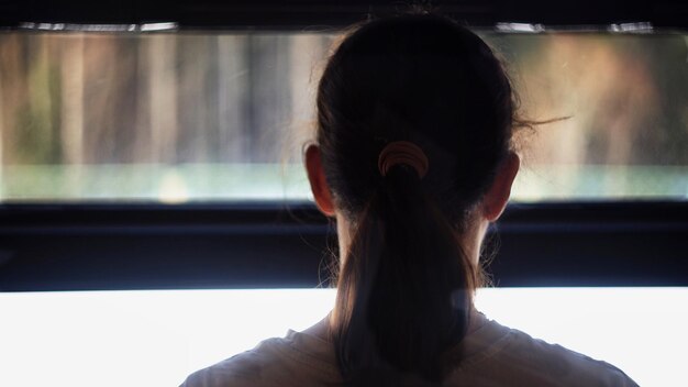 Vista trasera de una mujer mirando por la ventana