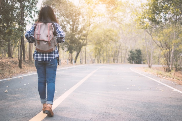 Foto vista trasera de una mujer con mochila caminando por la carretera