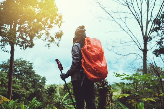 Vista trasera de una mujer con una mochila de pie en el bosque