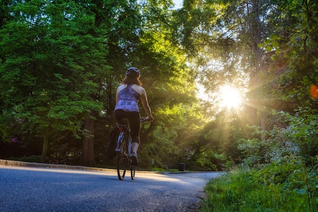 Foto vista trasera de una mujer montando una bicicleta en la carretera