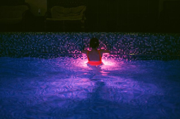 Foto vista trasera de una mujer nadando en la piscina