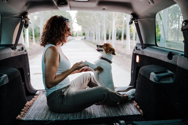 Foto vista trasera de una mujer con un perro sentado en el coche