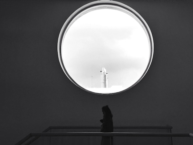 Vista trasera de una mujer de pie por la barandilla contra el cielo