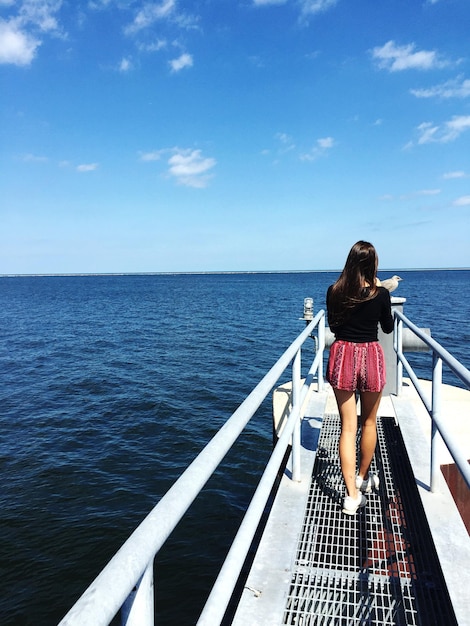 Foto vista trasera de una mujer de pie en un barco en el mar