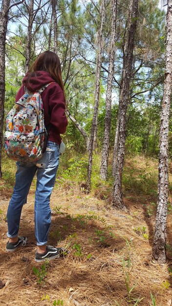 Foto vista trasera de una mujer de pie en el bosque