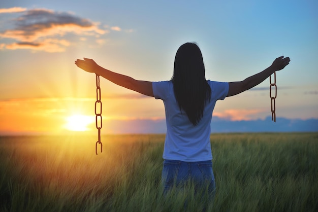 Foto vista trasera de una mujer de pie en el campo contra el cielo durante la puesta de sol