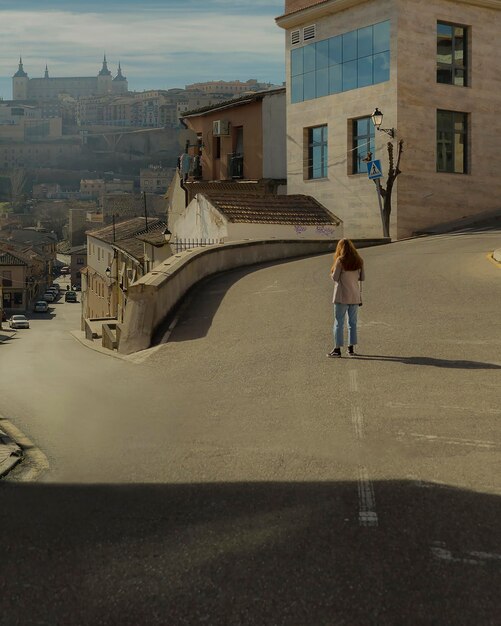 Foto vista trasera de una mujer de pie en la carretera en la ciudad