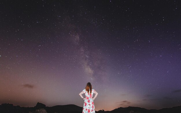 Foto vista trasera de una mujer de pie contra el cielo por la noche