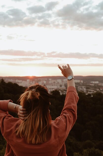 Vista trasera de una mujer de pie contra el cielo durante la puesta de sol