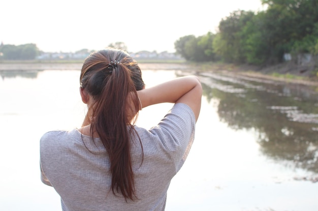 Foto vista trasera de una mujer de pie contra el lago