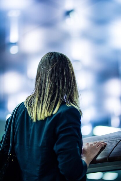 Foto vista trasera de una mujer de pie contra luces iluminadas